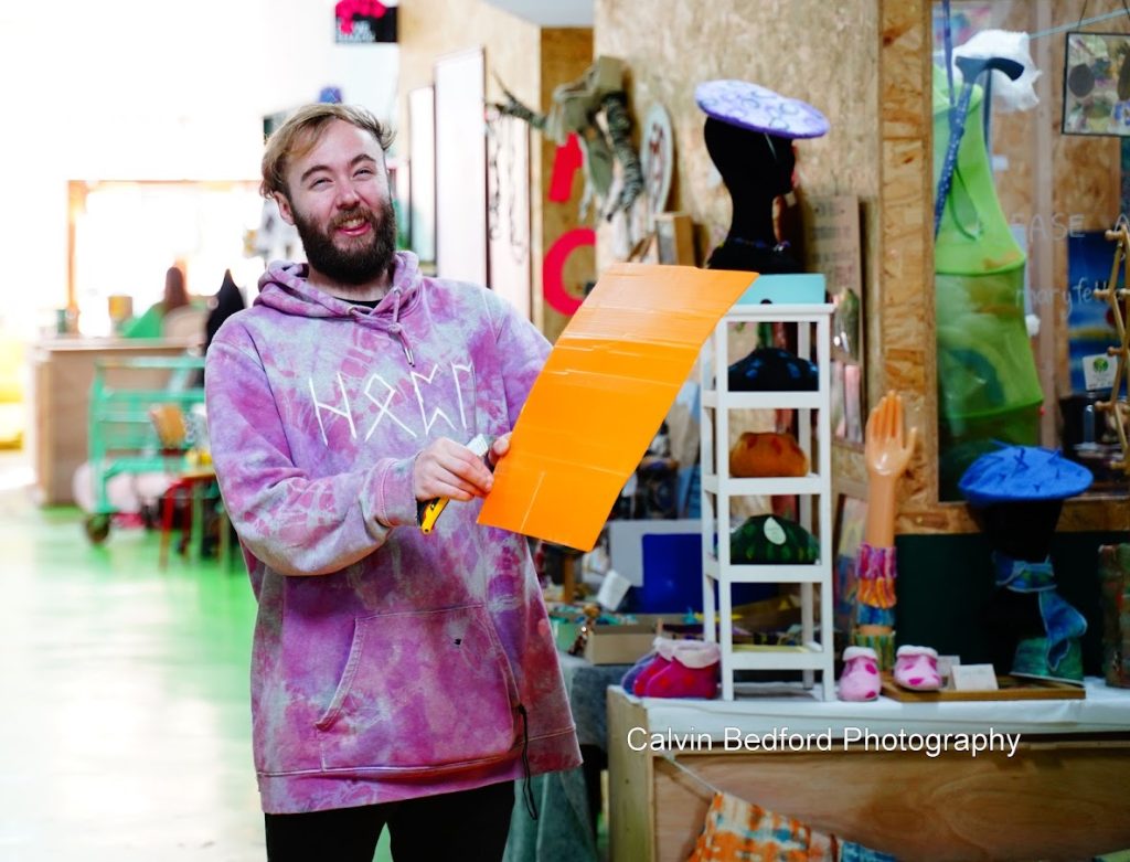 Workshop participnt holds up an orange bit af plastic waste to be shredded